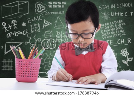 Asian student boy is writing on paper in classroom