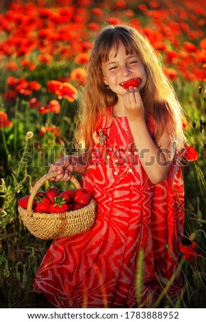 Girl in a field with poppies eating strawberries