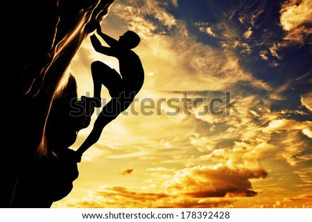 A silhouette of man free climbing on rock, mountain at sunset. Adrenaline, bravery, leader. Royalty-Free Stock Photo #178392428