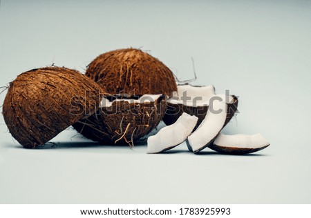 Parts of coconut on a colored background. Close up. Fresh ripe coconut broken into pieces