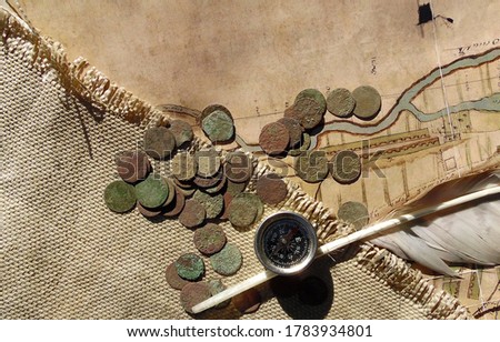 collage of vintage copper coins, compass and feather on old map and burlap background.
Archaeological discoveries, search for treasures and artifacts.
