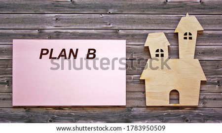 The text of plan B is written on a sticker, an icon of the house lies on a wooden table