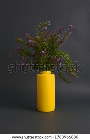 Lavender flower in a yellow glass vase on a dark black background
