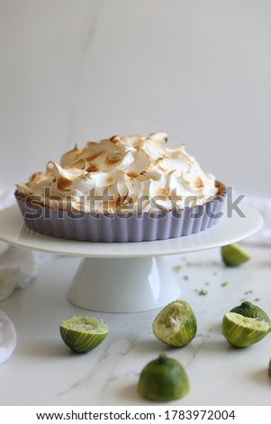 Classic Key lime pie topped with  meringue against white background, Traditional American dessert tart made of Key lime juice, egg yolks & sweetened condensed milk. Summer citrus fruit dessert concept