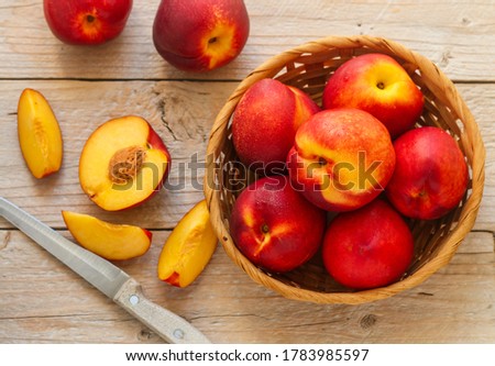 Nectarine. Ripe juicy organic nectarines (peaches) in a wicker basket. Whole and sliced fruit on a wooden table. Selective focus, top view Royalty-Free Stock Photo #1783985597