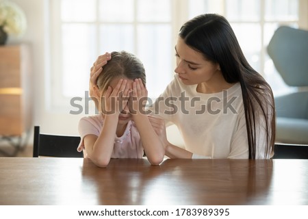 Caring mother calming and hugging crying upset little daughter, sitting at desk together, loving mum expressing support, comforting offended preschool girl, children psychologist concept Royalty-Free Stock Photo #1783989395