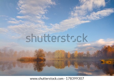 Beautiful Autumn Fall landscape over foggy misty lake