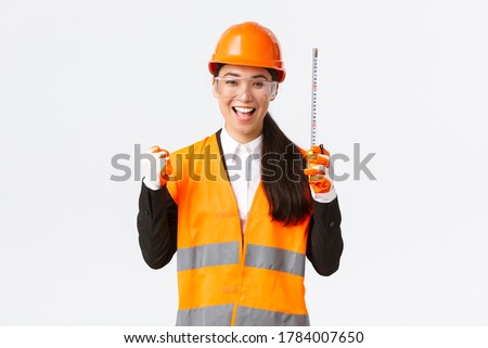 Successful winning female asian construction engineer finish work, achieve great results, fist pump cheerful and saying yes, holding tape measure, architect making right measurements, rejoicing