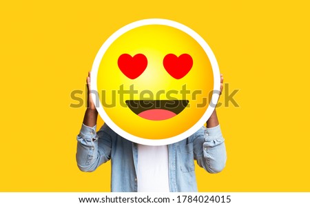 I Love Emoji. Unrecognizable Black Man Hiding Face Against Romantic Emoticon Sticker, Standing Over Yellow Background With Free Space Royalty-Free Stock Photo #1784024015