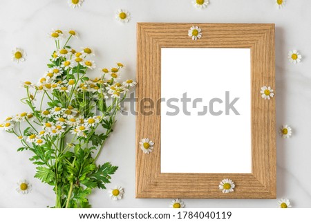 White chamomile flowers bouquet with blank photo frame on white background. mock up. flat lay. top view. wedding or holiday concept. festive background
