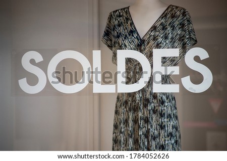 discount sign "SOLDES " in french,  the traduction of  (sales ) on window in french fashion store showroom on summer clothes background