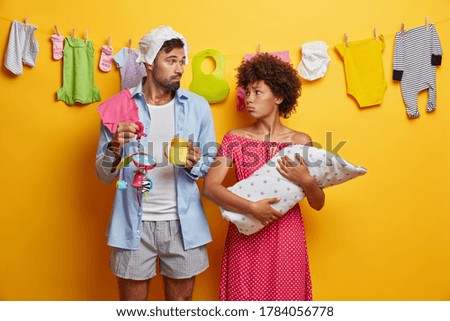 Concerned sad young parents cannot soothe crying newborn, feel upset because of childs illness, feel tired of infant nursing, wash clothes, feed and change diapers. Family and parenthood concept
