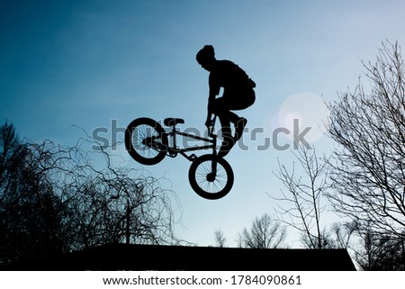 View from below strong athlete jumping in air. Guy performs tricks on a bike. Concept of adrenaline.