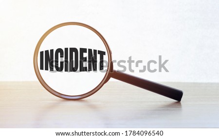 Magnifying glass with text INCIDENT on wooden table.
