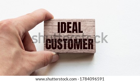 Hand of a businessman holding wooden blocks. Conceptual image. Text IDEAL CUSTOMER concept business succeed.