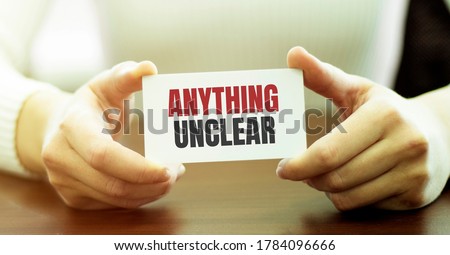 Businesswoman holding a card with text ANYTHING UNCLEAR