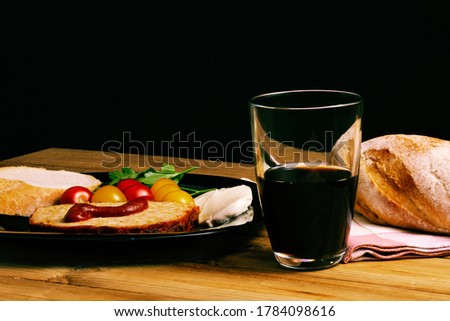 Classic meatloaf, cherry tomatoes, mozzarella, parsley, white bread in a black plate on a wooden background. Glass of pomegranate juice