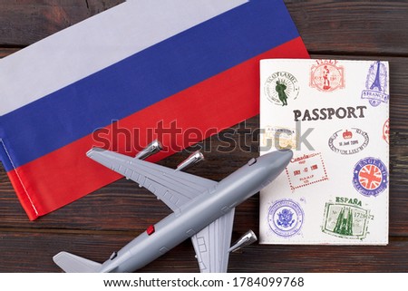 Flight to Russia and tourism concept. Toy airplane with passport and flag of Russia on dark wooden table.