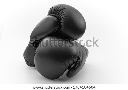 Competitive sports, fist protection and martial arts concept with photograph of two black boxing gloves with one glove on top of the other isolated on white background with clipping path cutout