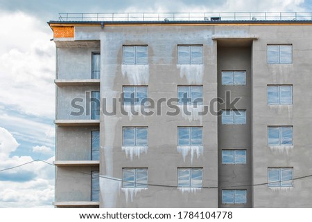Gray facade with a windows of a new under construction modern city house on a construction site