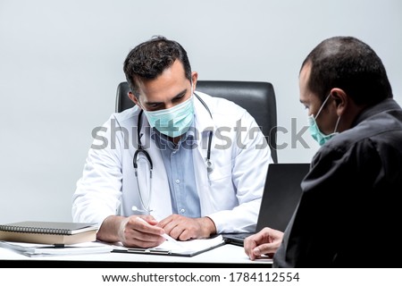 The Asian Muslim man doctor was sitting at the patient's examination table and was examining and talking about the patient with a smiling and worried face.