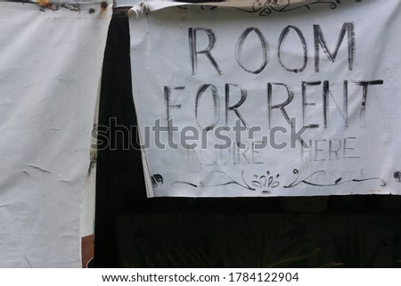 A fading Room for Rent signage hanging on the sidewalk