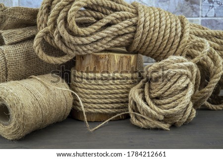 Jute rope and spools of burlap threads or jute twine in close-up on rustic wooden background Royalty-Free Stock Photo #1784212661