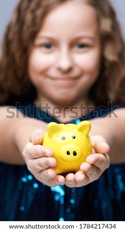 Piggy bank at young girl hands. Smile female face. Yellow moneybox. Child holding funny little savings. Success finance investing business.