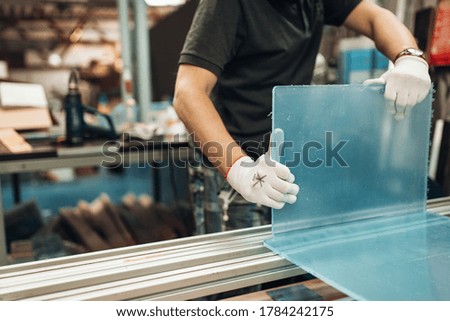 Worker bends plastic detail at the workshop. A man creates a new plastic part in a factory. The production process at the plant. Man in workshop weld a plastic acryl details Royalty-Free Stock Photo #1784242175