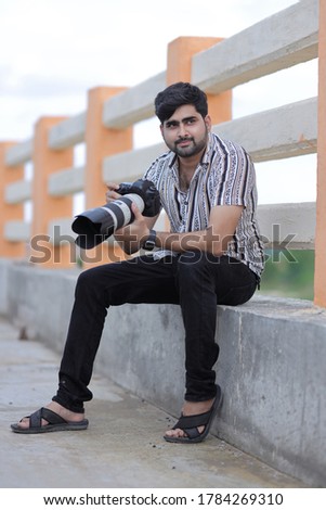 young indian photographer holding camera