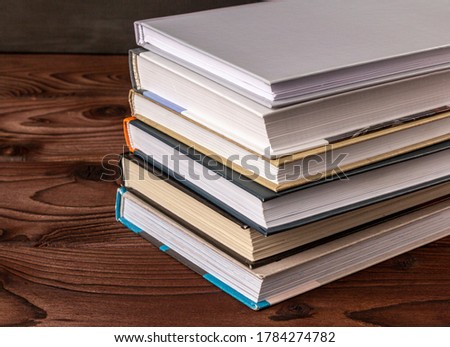 High angle close up of stack of books on wooden table. Books in the library on the table. Literature about business. Novels and tales, adventures, stories. The background for design