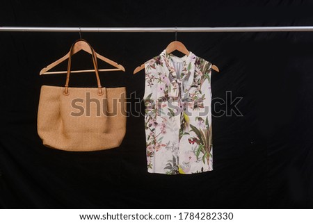 Female floral Leaves , pattern blouse and brown handbag on hanger-black background