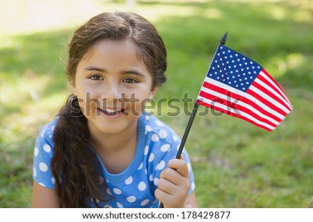 Close-up portrait of a young girl holding the American flag at the park