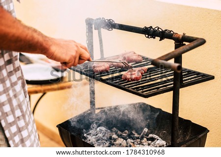 Close up of man cook meat with a barbeque bbq grill - restaurant and home outdor kitchen concept  - people and food