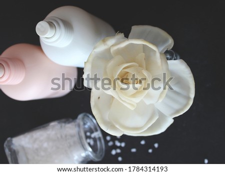 Fragrance flower close up. Bottles of perfumes and bath salt around. Black background. 
