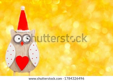 Christmas owl. New Year and Christmas card. Owl in a red Santa Claus hat is on a gold background with bokeh. Space for text