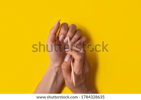 Close-up of a woman makes herself a manicure on a yellow background, top view. Manicure concept, flat lay