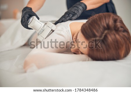 Cropped photo of beautician treating skin of lady with cavitation device in order to improve its form