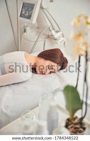 Cropped photo of a beautiful brunette woman relaxing at beauty salon with closed eyes