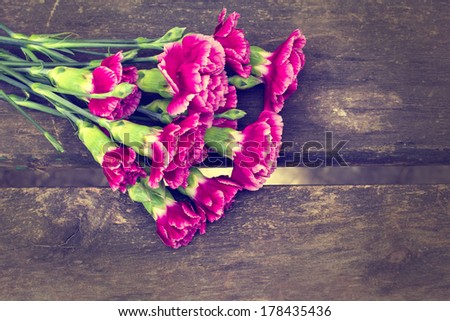 Fresh flowers carnations on aged wooden background. Toned image, rustic style. Selective focus.