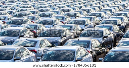 Rows of a new cars parked in a distribution center on a car factory on a sunny day. Top view to the parking in the open air. Royalty-Free Stock Photo #1784356181