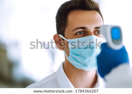 Office workers must go through fever measures using infrared digital thermometer check temperature measurement on the forehead during the coronavirus pandemic. Covid-19.  Royalty-Free Stock Photo #1784366207