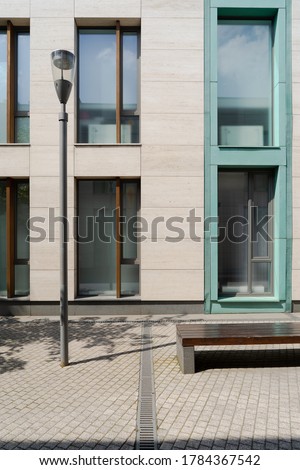 The facade of the house with large windows in the floor is lines with natural stone. Modern architecture. The facade of the house with a lantern and bench.