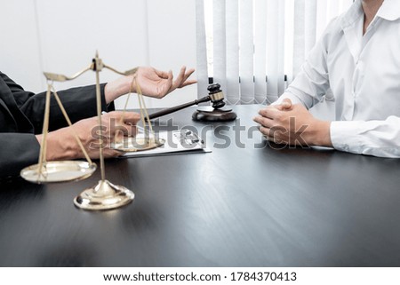 A male lawyer or a judge counseling clients about judicial justice and prosecution with scales, judges gavel, legal documents legal services concept.