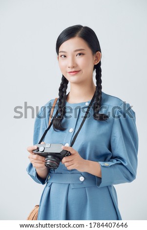 Young beautiful woman photographer is holding the camera and looking into the camera
