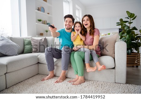 Full length photo of dream three people mommy daddy small kid  watch film remote control switch have rest sit cozy couch in house indoors