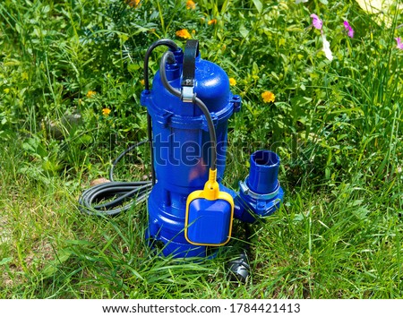 Fecal, submersible, drainage pump in blue. On the green grass. Royalty-Free Stock Photo #1784421413
