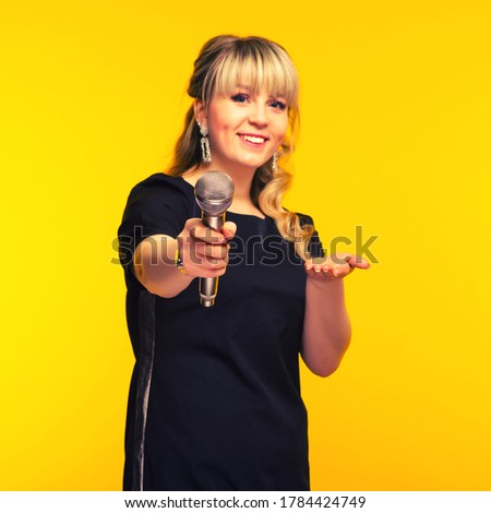 Presentation, public speech, conference, broadcasting, advertising. Cheerful young businesswoman, reporter, TV presenter holding microphone isolated bright yellow background. Focus on mic