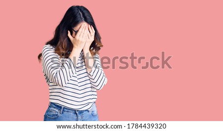 Beautiful young brunette woman wearing casual clothes and glasses with sad expression covering face with hands while crying. depression concept. 
