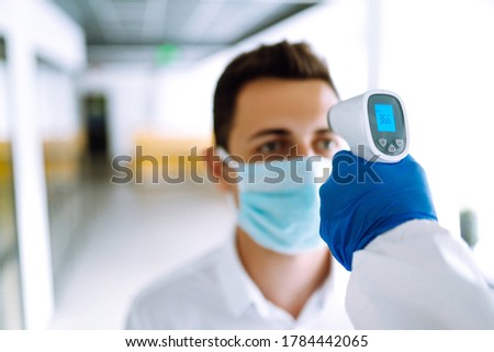 Сhecking the temperature of office workers during the coronavirus pandemic. Covid-19. Royalty-Free Stock Photo #1784442065